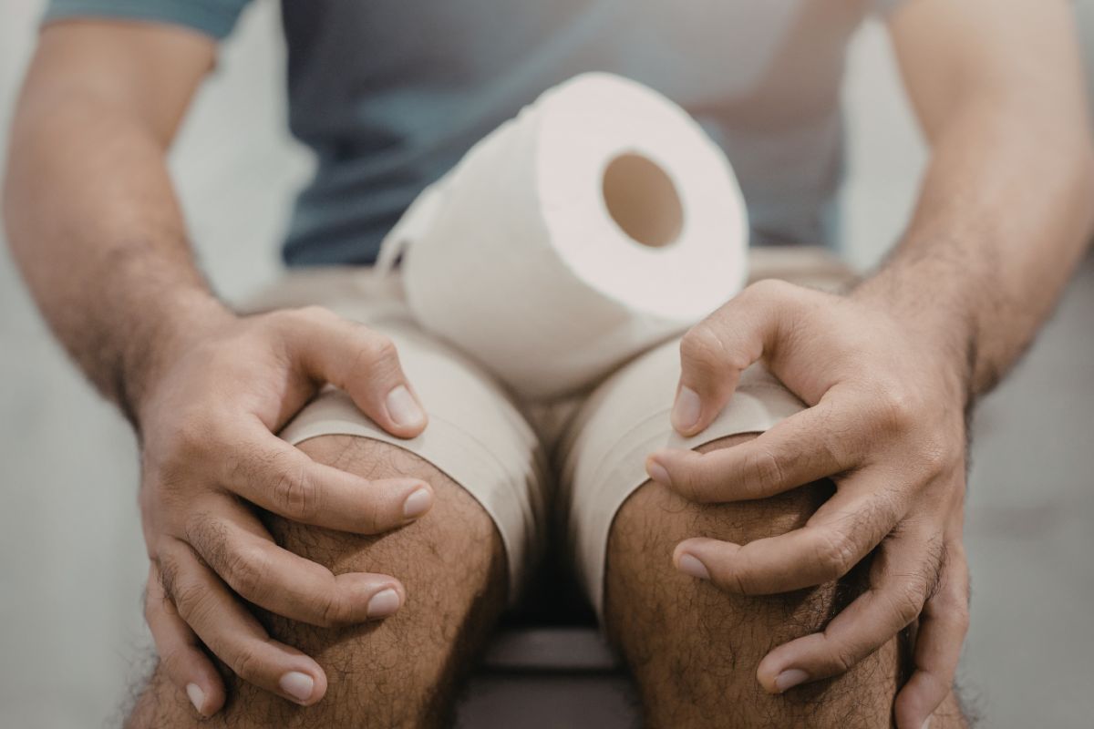 uomo sul water con rotolo di carta igienica sulle gambe